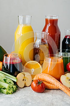 Vertical shot of fresh fruit and vegetable juice in glass bottles, different ingredients, white background. Healthy eating and
