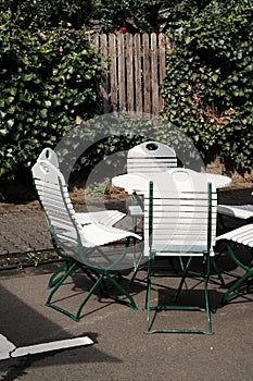 Vertical shot of the garden table and chairs with a wooden fence covered in ivy on a background