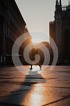 Vertical shot of a girl walking outside Duomo di Milano in Italy during sunset