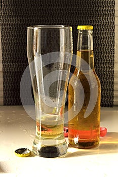 Vertical shot of a glass and a bottle of cold beer on a white table