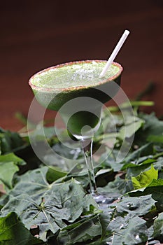 Vertical shot of a glass of chaya cocktail with a straw on mint leaves