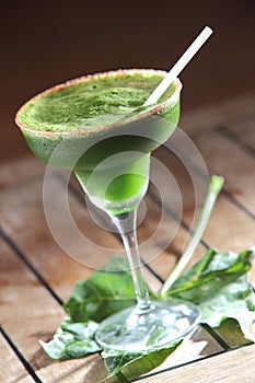 Vertical shot of a glass of chaya cocktail with a straw on a wooden table