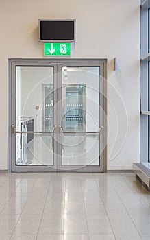 Vertical shot of a glass door and an emergency exit sign above the door
