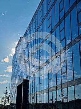 Vertical shot of the glass exterior of a modern company building under blue cloudy sky
