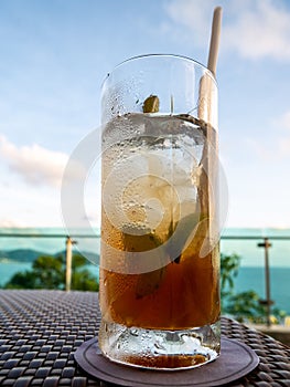 Vertical shot of a glass of iced drink with lime slices and a straw on the table