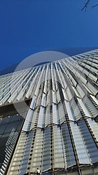 Vertical shot of a glass wall of a skyscraper under the blue sky