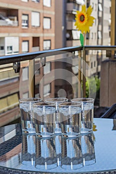 Vertical shot of glasses of ice water on a glass table on the balcony of the house