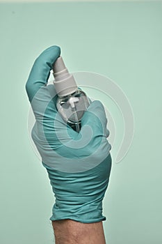 Vertical shot of a gloved hand holding a bottle of sanitizer