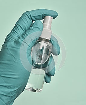 Vertical shot of a gloved hand holding a bottle of sanitizer