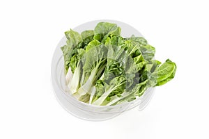 Vertical shot of green leafy vegetables on a glass bowl isolated on a white background