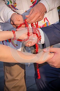 Vertical shot of handfasting ceremony using a red beaded cord