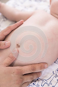 Vertical shot of hands doing a belly massage for baby - abdominal pains in nfants