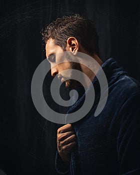 Vertical shot of a handsome caucasian male in a bathrobe on black background