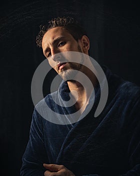 Vertical shot of a handsome caucasian male in a bathrobe on black background