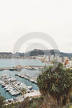 Vertical shot of a a harbot full of boats and yatchs with coastline buidings and mountains photo