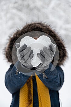 Vertical shot of a heart made of snow in the hands of a person