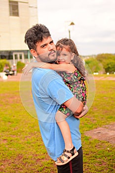Vertical shot of Hispanic father hugging his daughter on the street