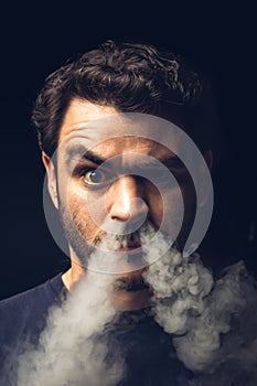 Vertical shot of a Hispanic man blowing smoke out of his nostrils