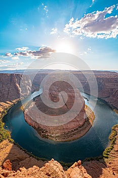 Vertical shot of the Horseshoe Bend in Arizona, United States, with the sun shining in the blue sky