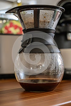 Vertical shot of hot coffee in a container with a drainer on top of it under the lights