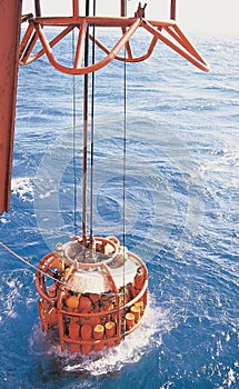 Vertical shot of a hyperbaric deep dive chamber in the sea hanging next to DSV ship