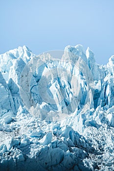 Vertical shot of icy glaciers and wild nature in Alaska in blue sky background