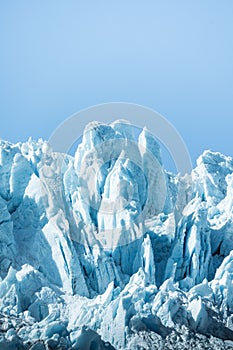 Vertical shot of icy glaciers and wild nature in Alaska in blue sky background