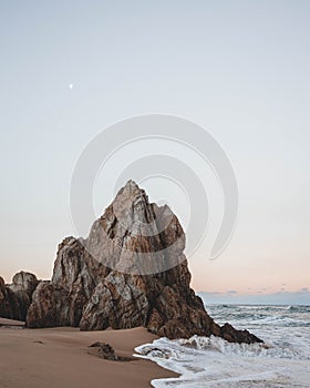 Vertical shot of an idyllic sandy coast with rocky cliffs at sunset