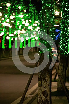 Vertical shot of illuminated tree trunks of the Impression Water street in Meishan city, China