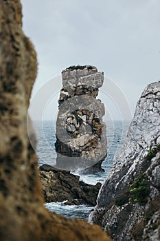Vertical shot of an immense rock formation with a wavy seascape view in Peniche, Portugal