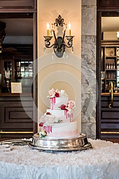 Vertical shot of an incredible wedding cake decorated with edible red white and pink roses