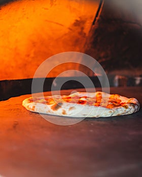 Vertical shot of an Italian pizza baking in a wood-fired oven