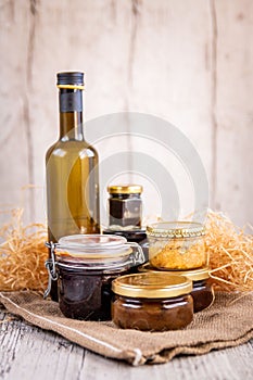 Vertical shot of jars of homemade cooking products and a bottle of olive oil for a gift basket