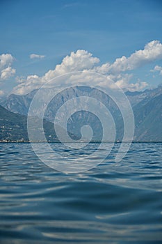 Vertical shot of Lake Como and mountains around it under blue cloudy sky in Lombardy region, Italy