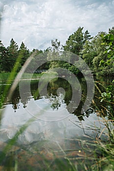 Vertical shot of a lake in the green forest on the Skie Island with the clouds in the sky photo