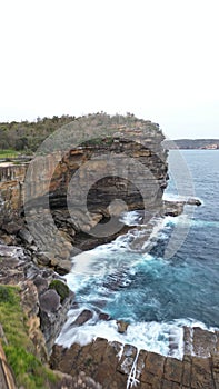 Vertical shot of a large rock formation jutting out from the surface of a choppy ocean