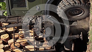 Vertical shot of large timber truck hauls cut trees and kicks up dust from the road