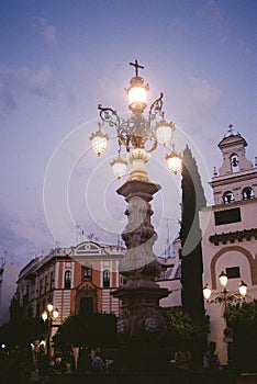 Vertical shot of a lighted street light in front of beautiful concrete buildings under cloudy sky