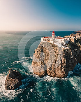 Vertical shot of a lighthouse on the edge of a cliff over the beautiful ocean under the blue sky