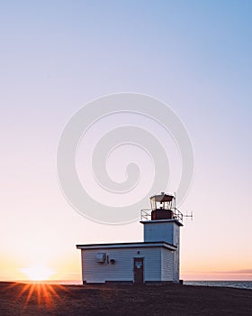 Vertical shot of a lightstation by the coast at sunset photo