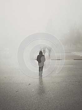 Vertical shot of a lonely man walking on the street on a foggy day