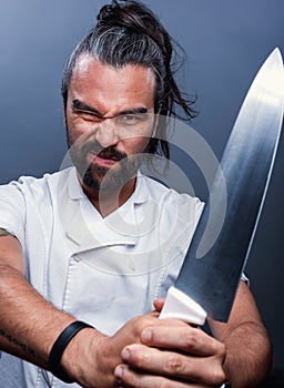 Vertical shot of a male chef holding a knife with a fierce face