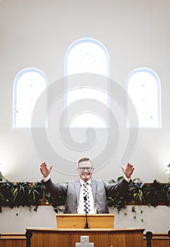 Vertical shot of a male in a suit preaching words of the Holy Bible at the altar of a church