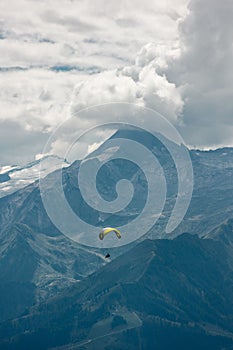 Vertical shot of a man on a paraglider with Schmittenhohe mountains in the background, Austria photo