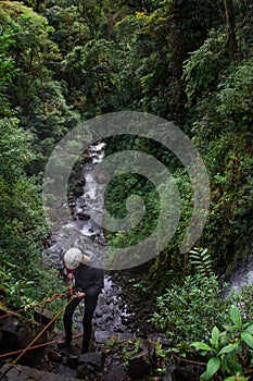 Vertical shot of man rappelling down a large waterfall in the middle of the tropical forest in Costa Rica