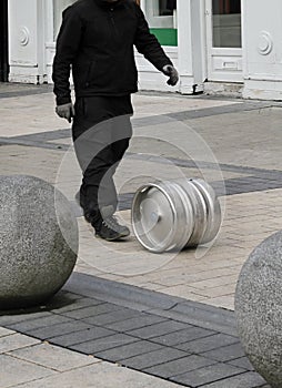 Vertical shot of a man rolling a circular metal tube on the street