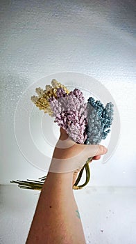 Vertical shot of man's hand holding a bouquet of artificial flowers