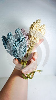 Vertical shot of man's hand holding a bouquet of artificial flowers