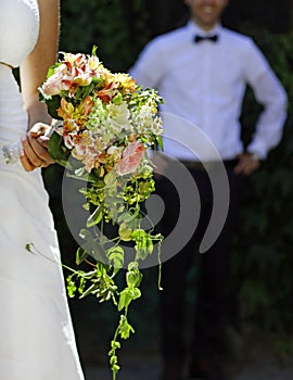 Vertical shot of a man standing behind the bride holding flowers in her hands