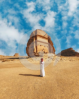 Vertical shot of a man standing in front of the Tomb of Lihyan son of Kuza in Saudi Arabia photo